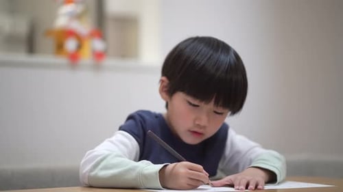 Child Drawing with Pencil at Table Indoors