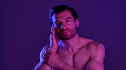 Muscular Man Posing in Purple Lighting with Towel