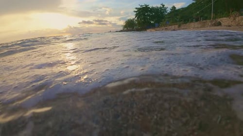 Slow Motion of Waves Lapping on Sandy Beach at Sunset