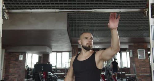 A Man in the Gym is Doing Strength Exercises to Build Muscles