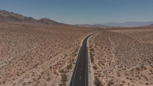 Aerial shot of car driving through Mojave desert on a sunny day
