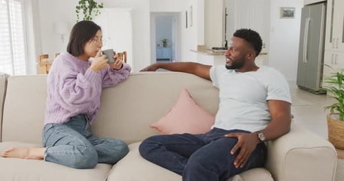 Young Couple Talking on Sofa in Living Room