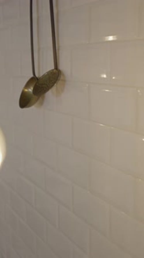 Handheld Shot of Decorative Pots By Tile Wall and Hanging Light Bulb