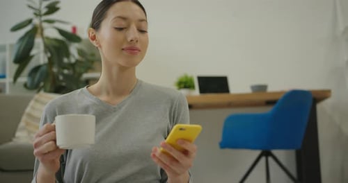 Woman Using Mobile Phone With Coffee At Home