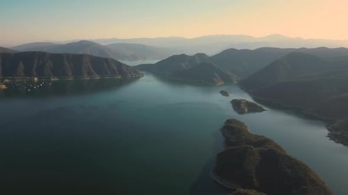 Aerial drone flying over a lake, water dam, with mountains at sunrise. Beautifull dreamy landscape