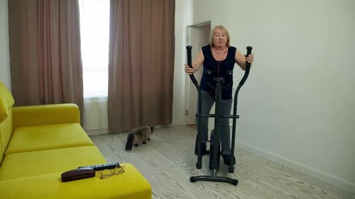 Senior Woman Exercising on Elliptical Machine at Home