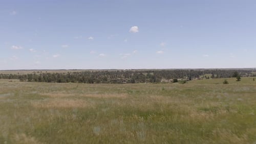 Aerial views of a grassy plane heading to a beautiful rock formation in Palmer Lake Colorado