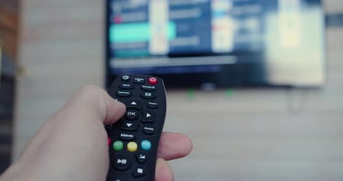 Nahaufnahme einer männlichen Hand, die die TV-Fernbedienung hält, Smart Television