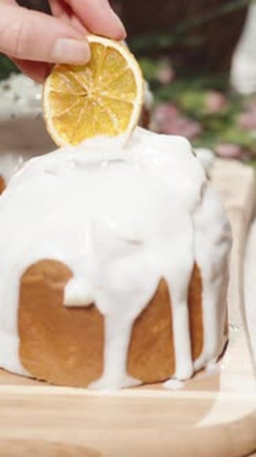 Vertical video. The woman decorates the top of the Easter cake with a dried orange slice.