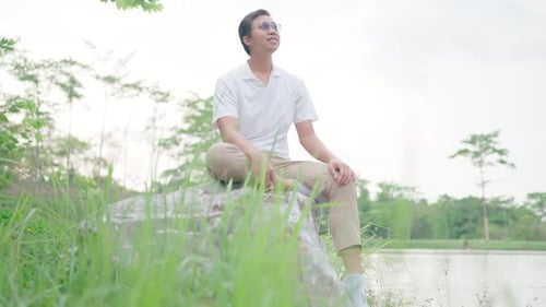 Man sitting and relaxing in nature. On the big rocks by the lake Feel love, happiness, smiles, still