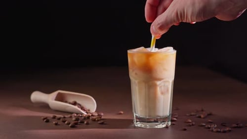 Adding Straw to Iced Coffee Drink with Beans