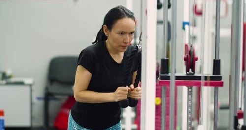 A Dedicated Woman Works Her Triceps Muscles with Controlled Reps in a Wellequipped Gym