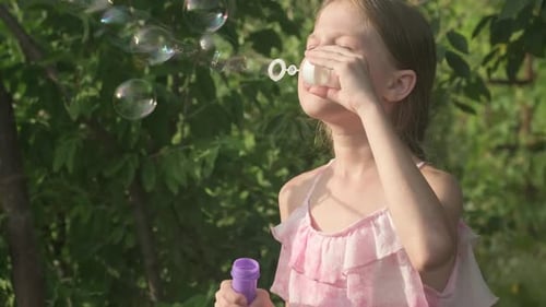 Joyful Girl Blowing Bubbles in the Sunlight