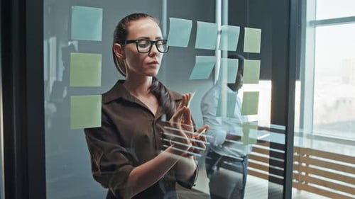 Female Employee in Glasses Writing on Stickers and Gluing Them