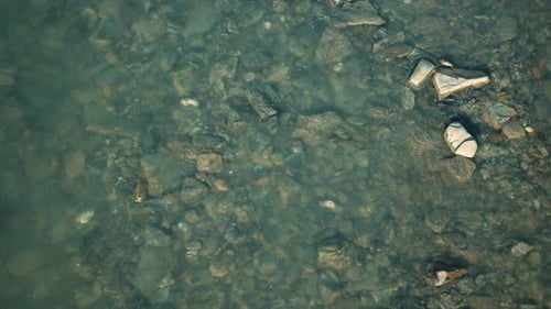 Close Up of Transparent Shallow Water Surface the Bottom is Strewn with Pebbles