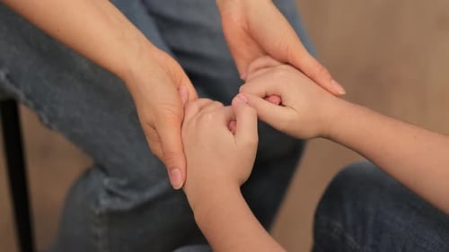 Adult Hand Holding Child Hands in Loving Support