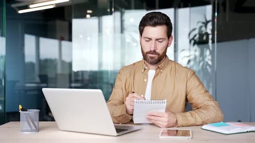 Webcam view. Confident businessman talking on a video call conference taking notes looking at camera