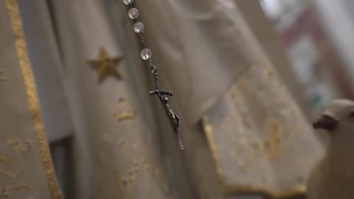 Close up of rosary crucifix against ornate vestments, symbolizing faith and devotion