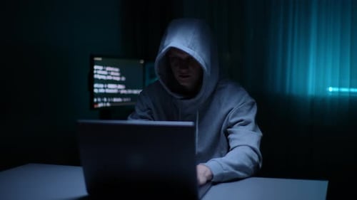 Vorderansicht eines heimlichen Hackers in Sweatshirt mit Kapuze, der auf der Tastatur tippt und das Passwort bricht