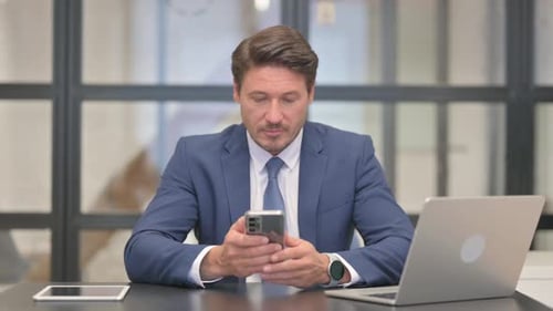 Man in Suit Using Phone in Office