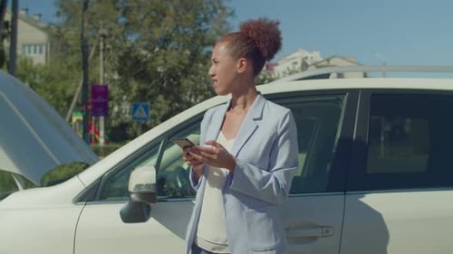 Woman With Car Trouble Using Smartphone on City Street