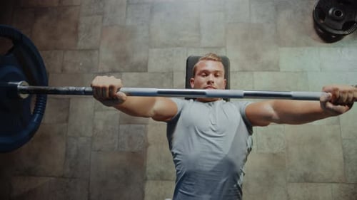 Top View of Professional Athlete Doing Bench Press Workout with a Barbell in the Hardcore Gym. Musc