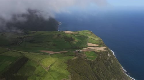 Aerial view of coastal cliffs and green fields in Portugal.