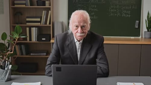 Smiling Senior Man at Desk in Computer Class