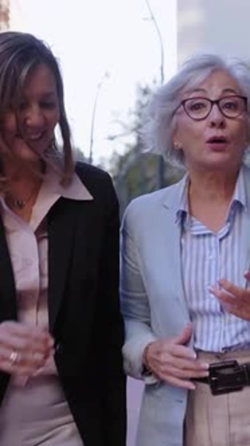 Three Mature Businesswomen Walking Outside Financial District Talking and Smiling Going to Work