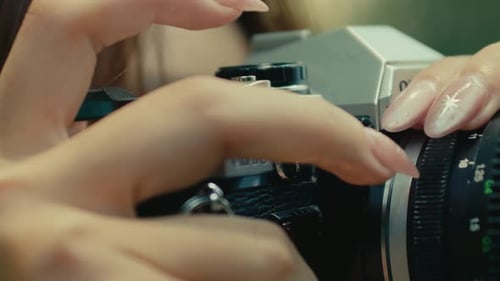 Nahaufnahme einer weiblichen Hand mit langen Nägeln, die den Auslöser drücken, auf einem alten Retro-Kamerafilm