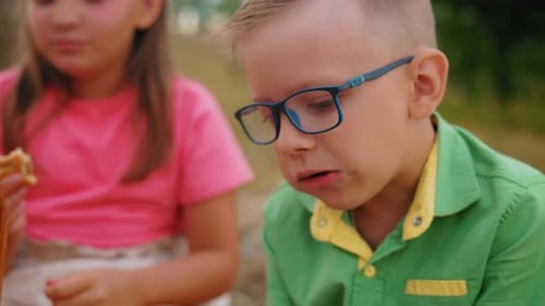 Happy Boy Eating Pastry Outdoors in Summer