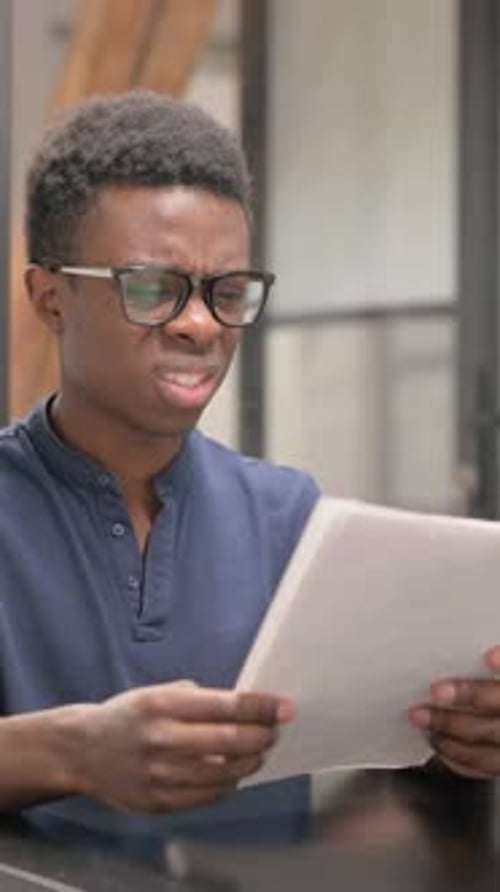 Worried Man Reads Document Indoors at Desk