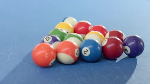Camera is moving back tilting up, revealing rack of billiard balls on blue pool table