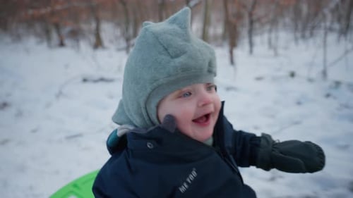 Baby auf einem Schlitten, der über den Schnee gleitet