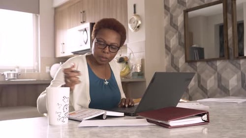 Woman Works at Table with Laptop and Notebook
