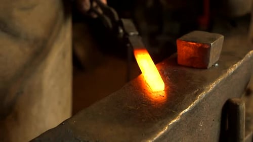 Blacksmith Forges Red Hot Metal Bar on Anvil.