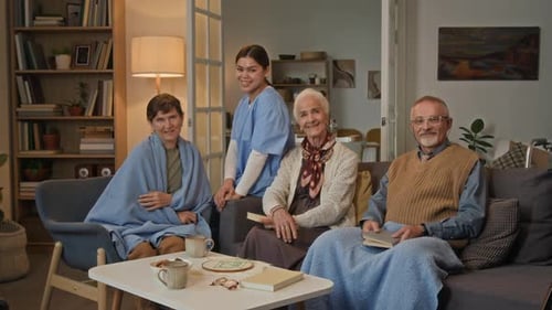 Elderly People Relaxing Indoors with a Young Adult Caregiver