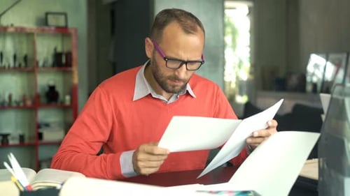 Man Reviewing Documents at Desk in Home Office