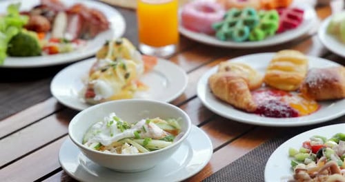 Assorted Breakfast Buffet on Wooden Table Featuring Eggs Benedict