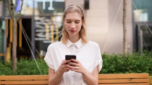Woman Using Phone While Sitting on Bench
