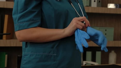 Gros plan d'une infirmière mettant des gants chirurgicaux en nitrile bleu avant l'examen