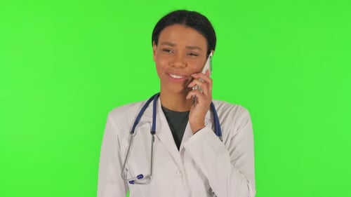 Portrait of Female Doctor Talking on phone on green background