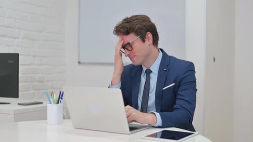 Frustrated Businessman Working at Laptop in Office