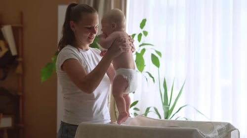 Loving Woman Holding a Baby in Diaper Indoors
