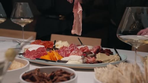 Le prosciutto est retiré du centre d'une planche à charcuterie pleine de vie (Ralenti)