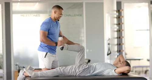Physical therapist stretching man's leg during rehabilitation session in clinic