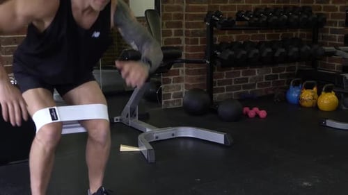Muscly man in home gym exercising resistance band squats