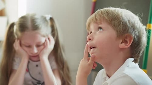Young Boy Thinking with Bored Girl in Background