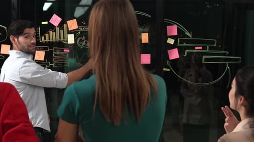 Team Brainstorming Together Using Sticky Notes on Glass