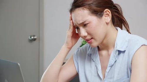 Woman Experiencing Headache in Front of Laptop